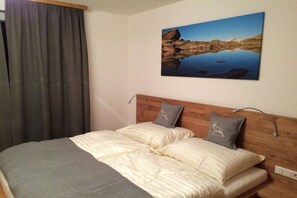 A bed with a wooden headboard, two pillows, and a blanket. - Alpine Chalet Hohe Tauern (Matrei i. Osttirol)