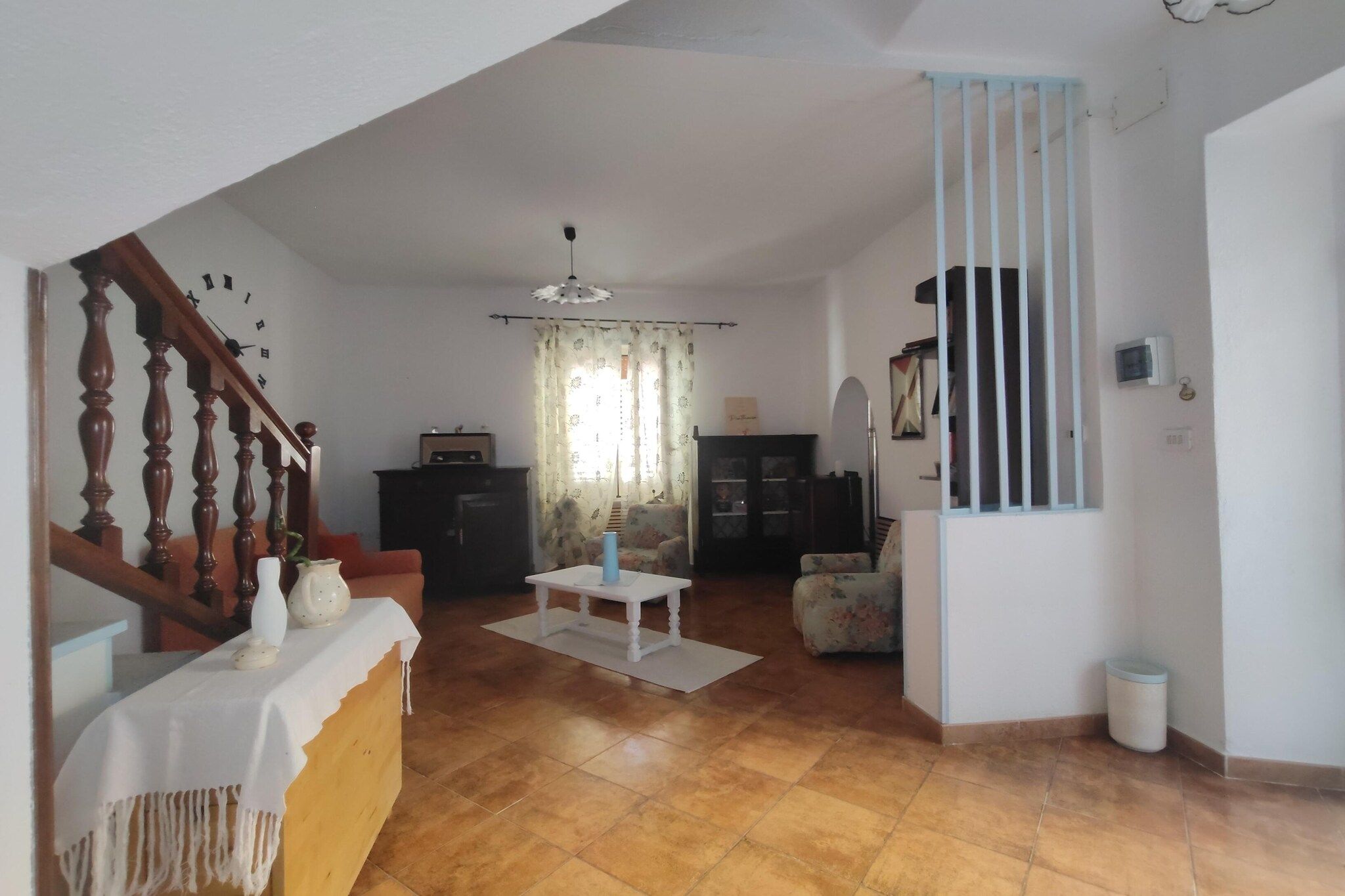 A living room with a staircase, a dining area, and a kitchen.