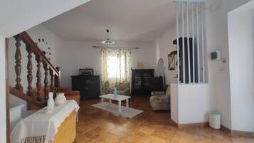 A living room with a staircase, a dining area, and a kitchen.