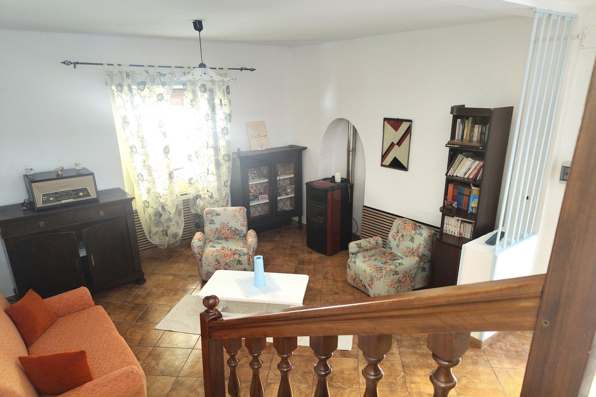 A living room with a sofa, chairs, a table, a cabinet, and a bookshelf.