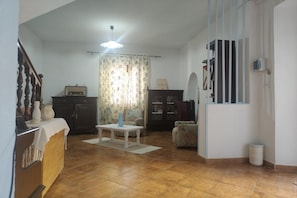 A living room with a tiled floor, a white table, a sofa, a cabinet, and a ceiling fan. - Garden, terrace and private parking (Orgosolo (NU))