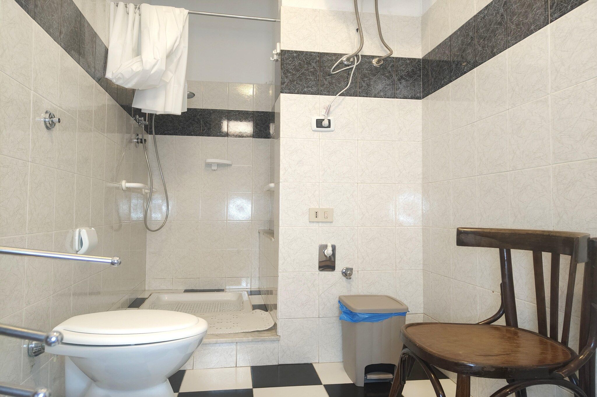 Ein Badezimmer mit Toilette, Dusche und einem Stuhl.