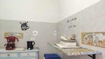A kitchen with a coffee maker, a kettle, and a shelf with a coffee-themed sign.