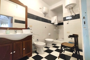 A bathroom with a sink, two toilets, a bidet, a mirror, and a checkered floor. - Garden, terrace and private parking (Orgosolo (NU))