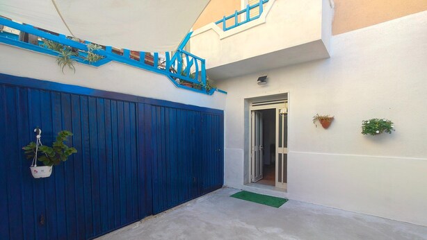Un cancello blu, una piccola scala, una porta e una pianta in vaso.