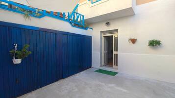 Un cancello blu, una piccola scala, una porta e una pianta in vaso.