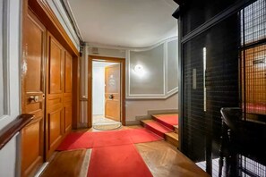 A hallway with wooden doors, a red carpet, and a staircase leading to an upper level. - Opera apartment in the heart of Paris (Paris)