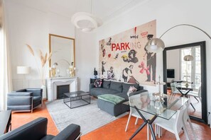 Un salon moderne avec une cheminée, un canapé, une table à manger en verre et une grande fresque murale.