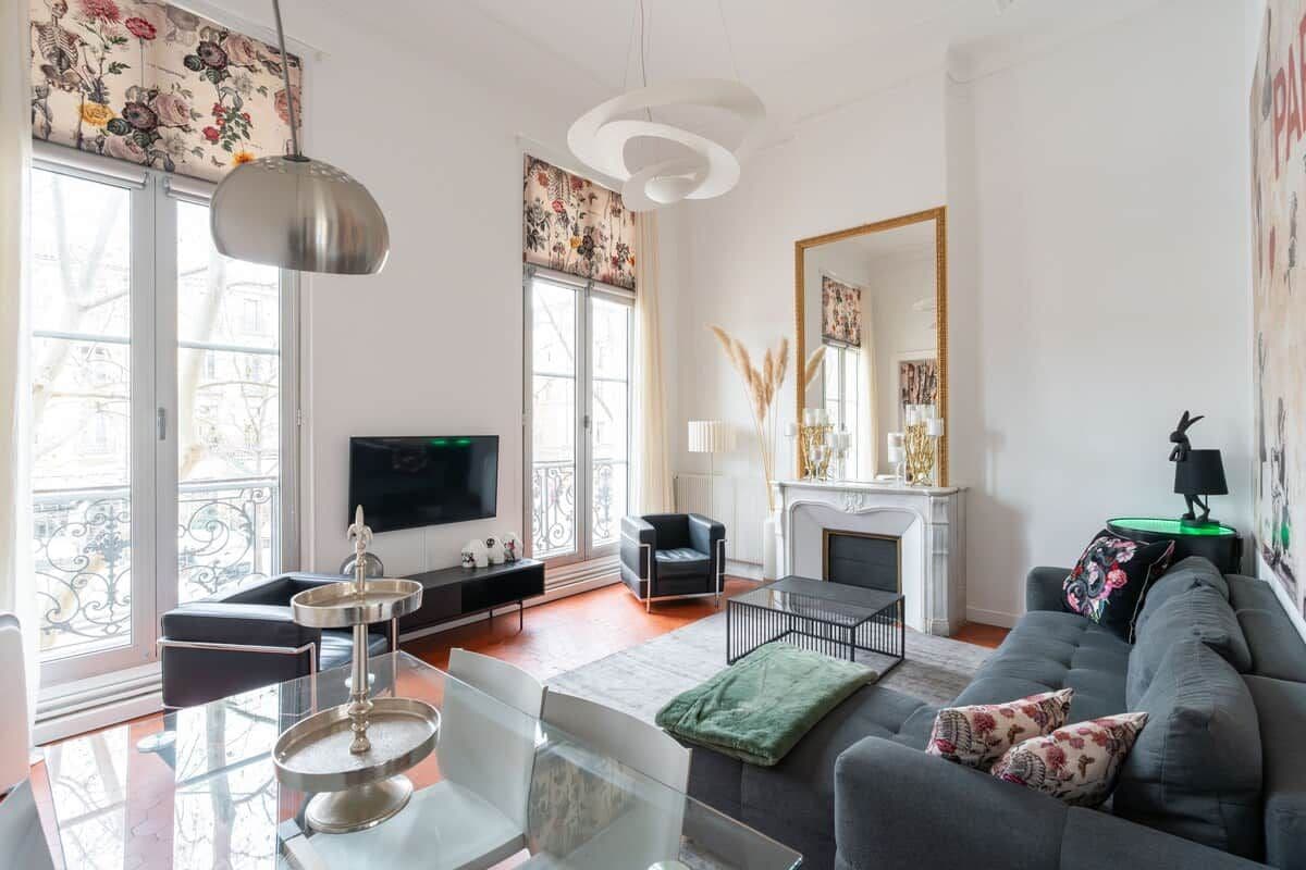 A modern living room with a sofa, a TV, a fireplace, and a dining area with a glass table.