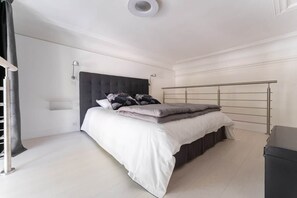 A bedroom with a bed, bedside lamps, a headboard, and a metal bed frame. - Appartement Mirabeau n°8 (Aix-en-Provence)