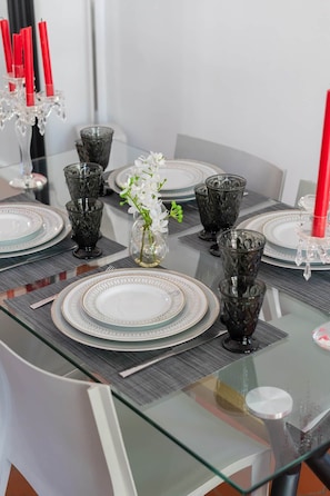 A dining table set with plates, glasses, and a vase with flowers. - Appartement Mirabeau n°8 (Aix-en-Provence)