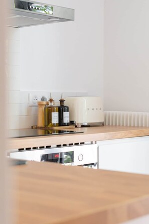 A kitchen with a white countertop, a built-in oven, and a white dishwasher. - Appartement Mirabeau n°8 (Aix-en-Provence)