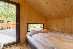 Ein Zimmer mit Bett, Fenster und Blick nach draußen.