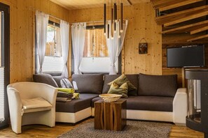 Ein gemütliches Wohnzimmer mit einer Couch, einem Sessel, einem Couchtisch und einem Fernseher.