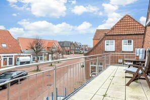 Ein Wohngebiet mit Ziegelfassaden, einer gepflasterten Straße und einem Balkon mit Gartenmöbeln.