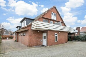 A two-story brick house with a covered porch and a small front yard. - Holiday apartment with 1 bedroom (St. Peter-Dorf)