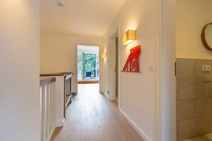 A hallway with a wooden floor, a staircase, and a red architectural feature on the wall. - Holiday home with 1 bedroom (St. Peter-Bad)
