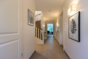 A hallway with a staircase, framed artwork, and wall-mounted lighting. - Holiday home with 1 bedroom (St. Peter-Bad)
