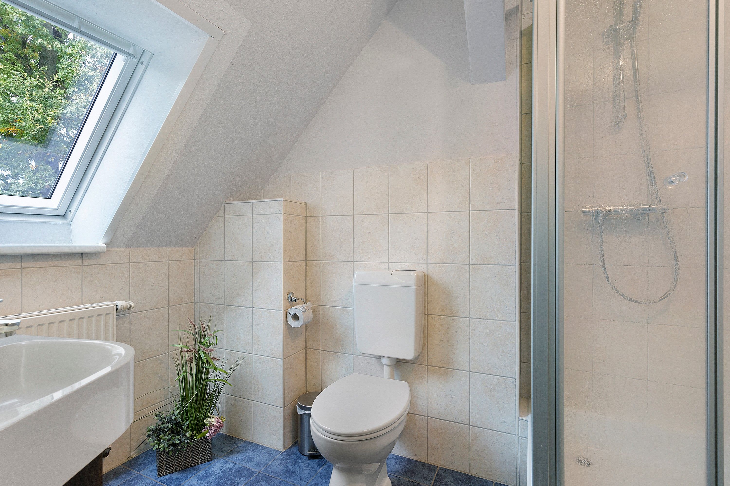 Ein Badezimmer mit Dachfenster, Toilette, Bidet und Waschbecken.