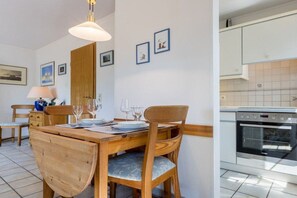 A dining area with a wooden table and chairs, a lamp, and framed pictures on the wall. - 1 in the house "Trischen" (ID 359) (St. Peter-Ording)