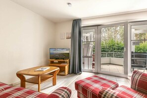 A living room with a television, a wooden coffee table, and a red plaid sofa. - Holiday apartment 2 in Haus Hever (ID 048) (St. Peter-Bad)