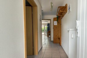 A hallway with a wooden door, a radiator, and a ceiling light fixture. - Holiday apartment 2 in Haus Hever (ID 048) (St. Peter-Bad)
