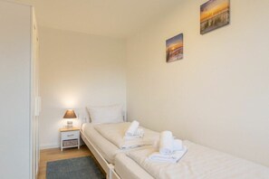 Ein Einzelzimmer mit Nachttisch, Lampe und kleiner Schublade.
