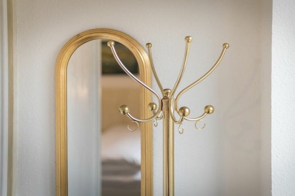 Ein goldrahmiger Spiegel mit einem Wandpaneel für Kleiderhaken.