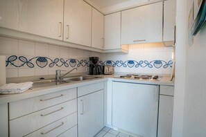 A kitchen with white cabinets, a stainless steel sink, and a patterned backsplash. - Apartment 14 (ID 212) (St. Peter-Bad)