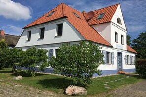 Ein zweigeschossiges Gebäude mit rotem Ziegeldach, einem kleinen Balkon und einem Schild, das es als Pension kennzeichnet.