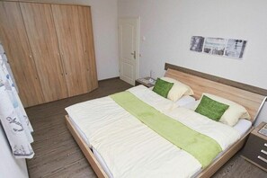 Ein Zimmer mit einem Einzelbett, einem Holzkopfstück, einem Nachttisch und einer Nachttruhe.