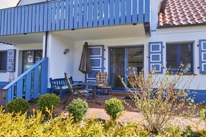 Ein Gebäude mit einer überdachten Terrasse, einer Treppe und einer Sitzgruppe mit Tisch und Stühlen.