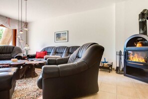 Ein Wohnzimmer mit einer Couch, Sesseln, einem Couchtisch und einem Kamin.