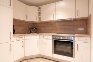 Eine moderne Küche mit weißen Schränken, einem Edelstahlbackofen und einer Holz-Spritzschutzwand.