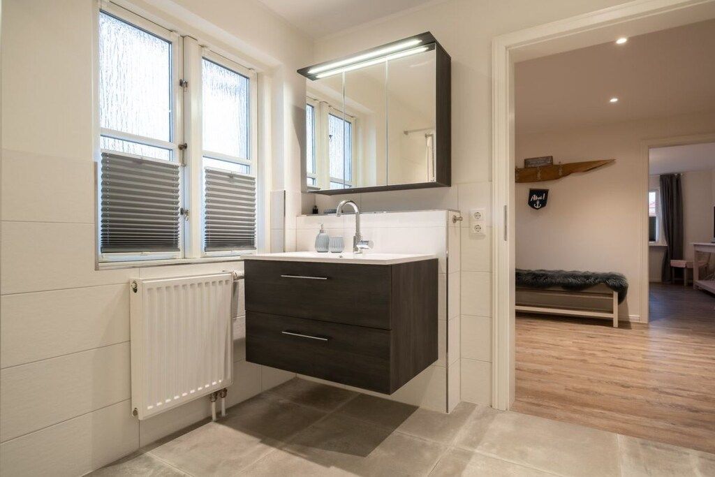 Et moderne badeværelse med væghængt skab, spejl og radiator.