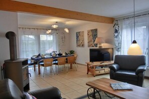 A living room with a fireplace, dining area, and a TV. - Holiday home in Graal-Müritz with terrace (Graal-Müritz)