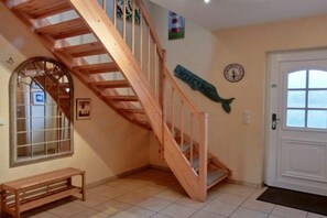 A wooden staircase leading to an upper floor, a welcome sign, a clock, and a bench in a room with tiled flooring. - Holiday home in Graal-Müritz with terrace (Graal-Müritz)