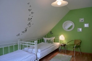 A bedroom with a white metal bed, green walls, a round mirror, and a small table with a lamp. - Holiday home in Graal-Müritz with terrace (Graal-Müritz)