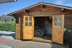 A wooden cabin with a bicycle inside, a door, and a small porch area. - Holiday home in Graal-Müritz with terrace (Graal-Müritz)