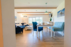 Ein modernes Wohnzimmer mit Essbereich, ausgestattet mit einer Couch, Sesseln und einem Tisch.
