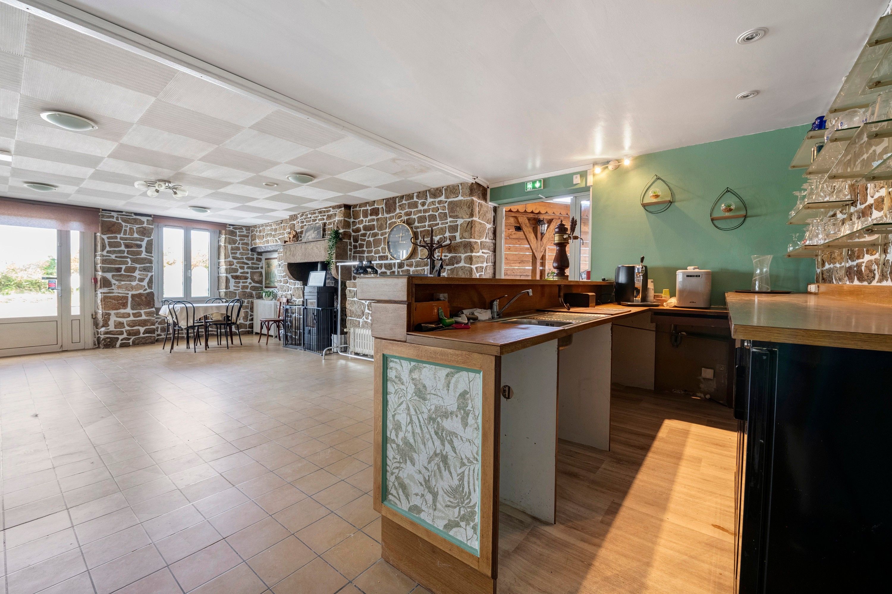 Un'ampia cucina con parete in pietra, un tavolo da pranzo in legno e un angolo bar.