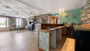 Un'ampia cucina con parete in pietra, un tavolo da pranzo in legno e un angolo bar.