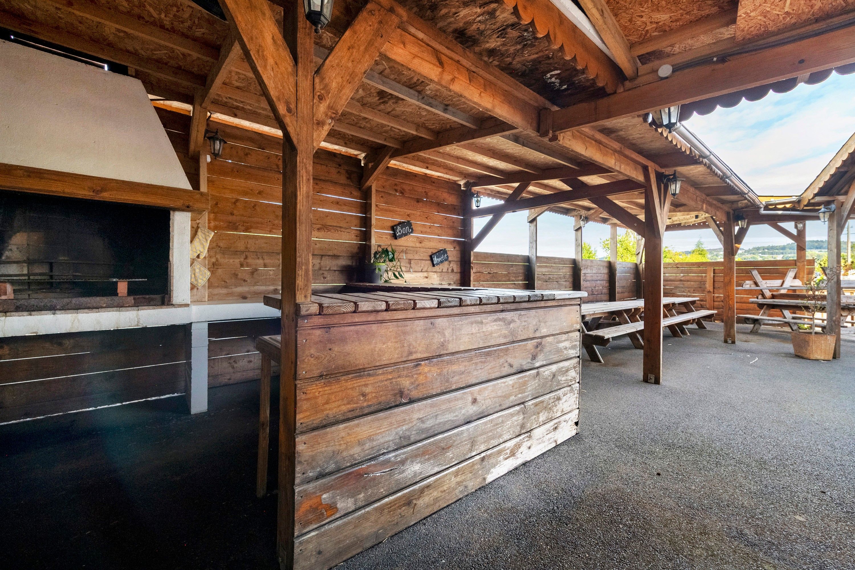 Un'area esterna rustica con panche e una griglia in legno.