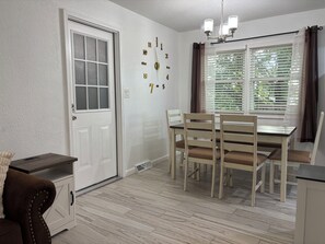 Ein Essbereich mit Tisch und Stühlen, einer weißen Tür und einem Fenster mit Jalousien.