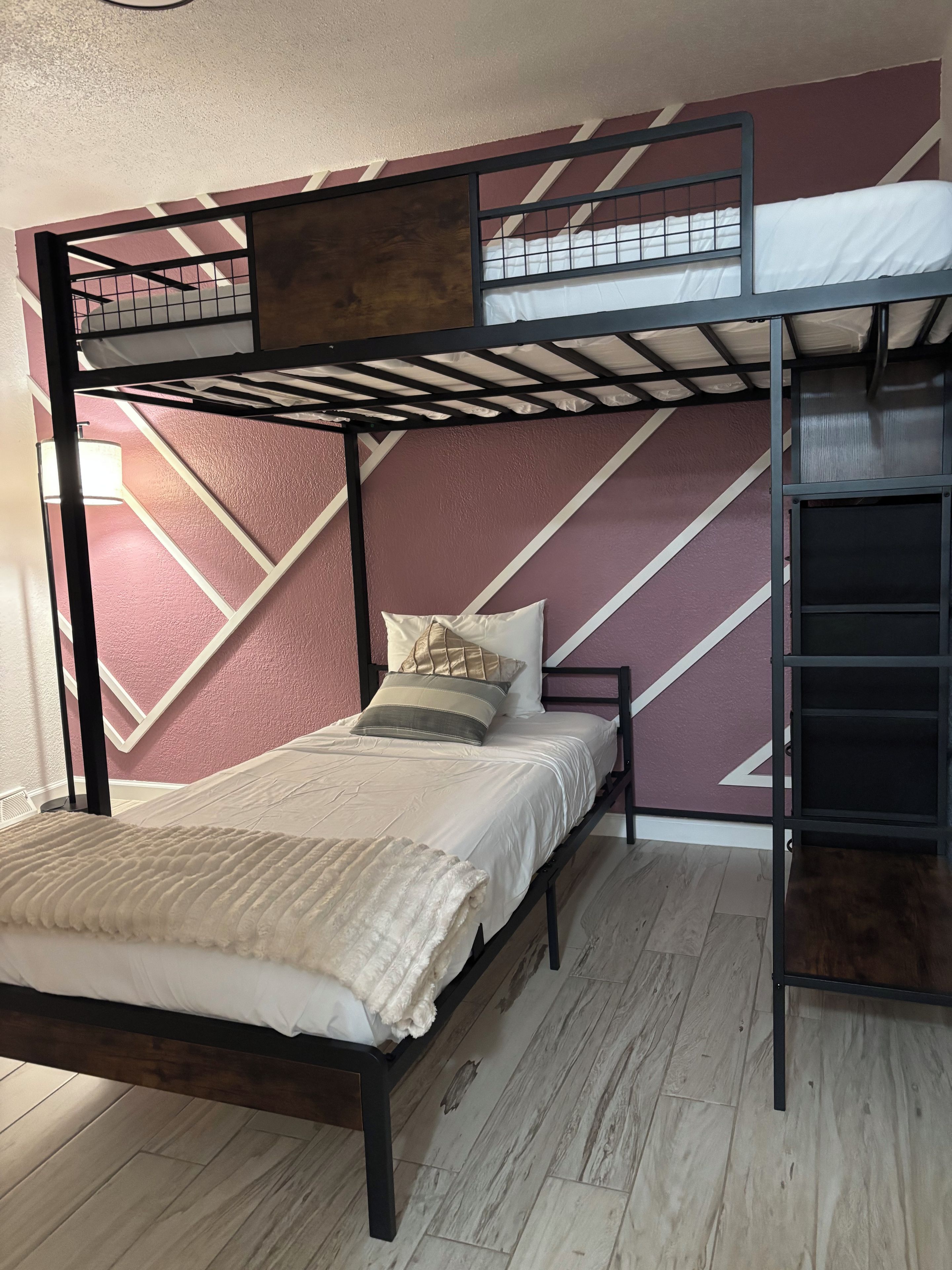 Un letto a castello con struttura in legno, materasso, cuscini e coperta.