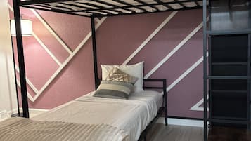 A bunk bed with a wooden frame, a mattress, pillows, and a blanket.