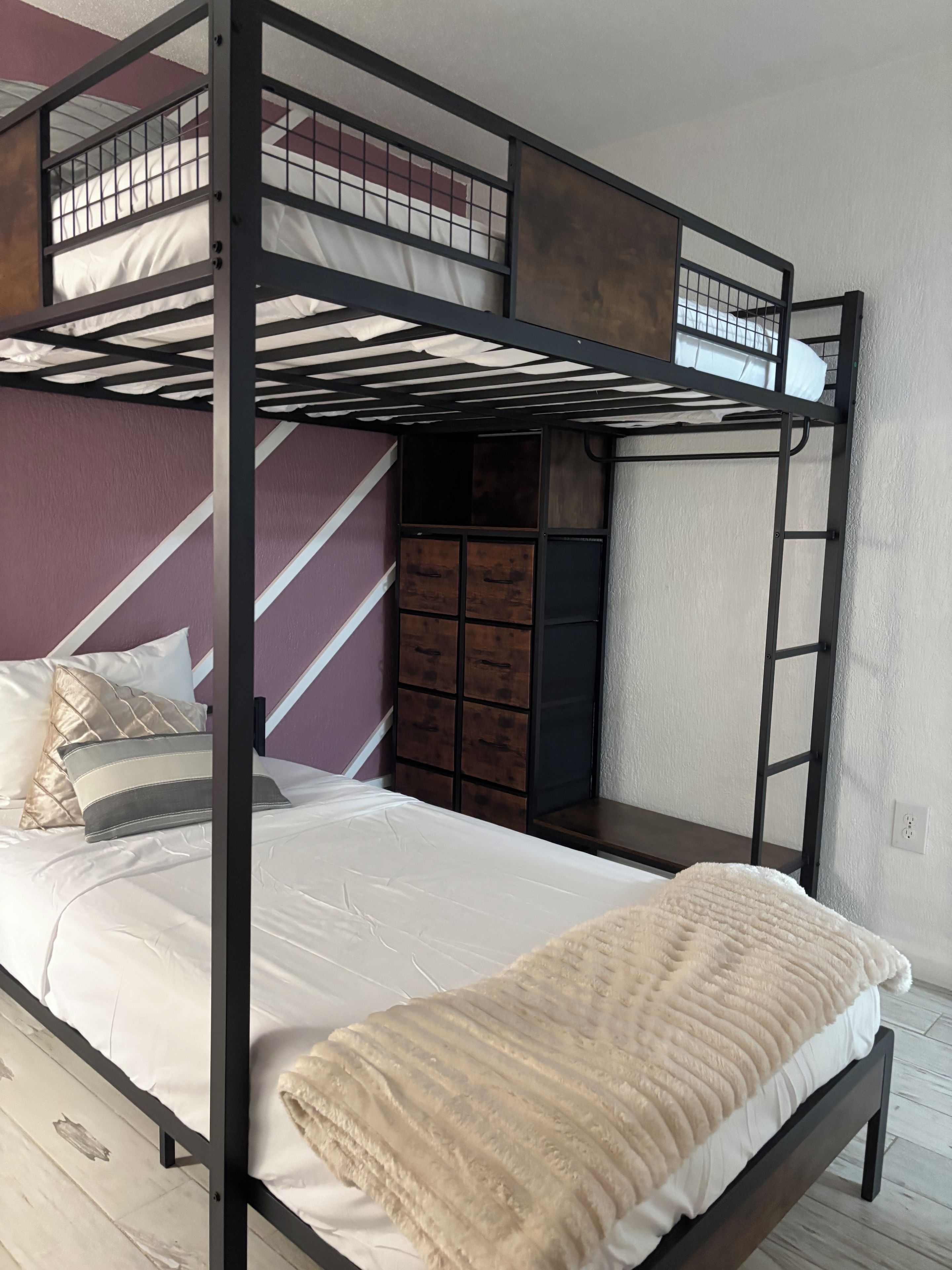A bunk bed with a lower level bed and a top bunk with a metal railing.