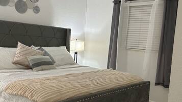 A bedroom with a bed, a ceiling fan, a nightstand, and a window with curtains.