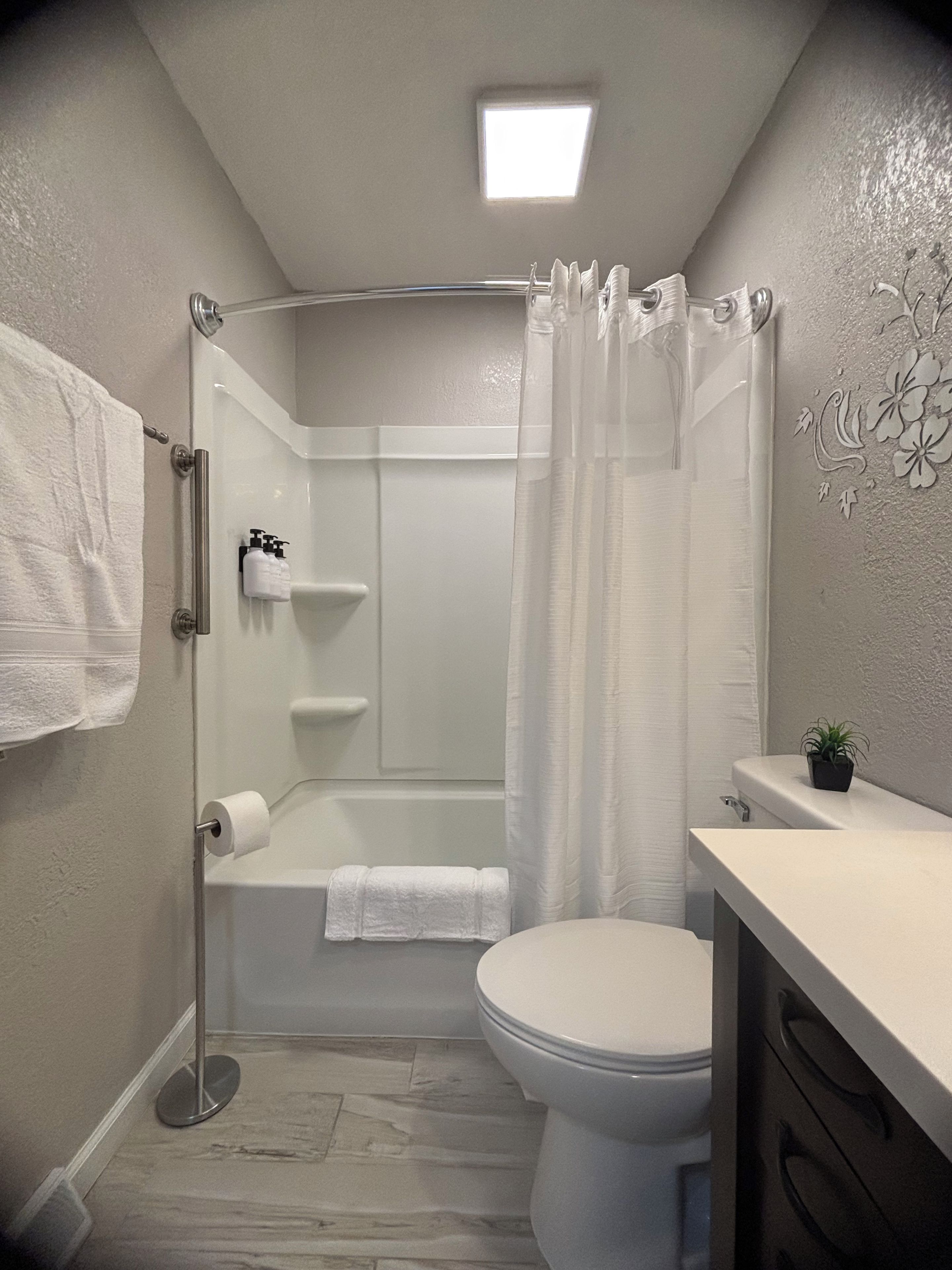 A bathroom with a shower, toilet, and sink.