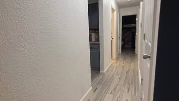 A hallway with white walls, a marble floor, and a door on the right.